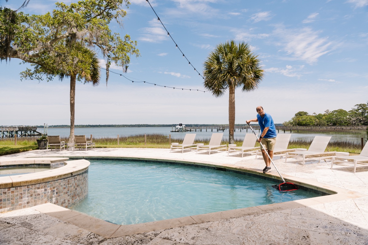 Pool technician skimming a waterfront pool on Johns Island, SC
